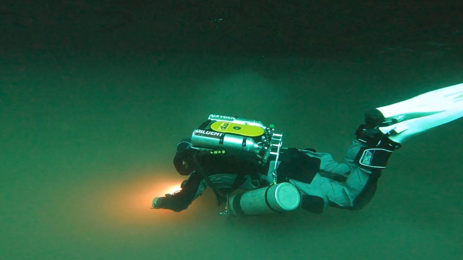 Diver on a rEvo closed-circuit rebreather gliding through a cenote, diluent and oxygen cylinders visible